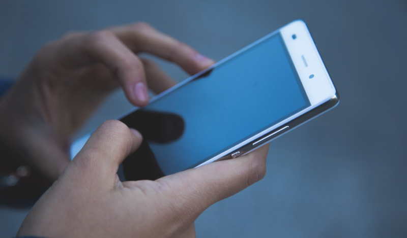Gambar tangan seseorang yang sedang mengakses smartphone.