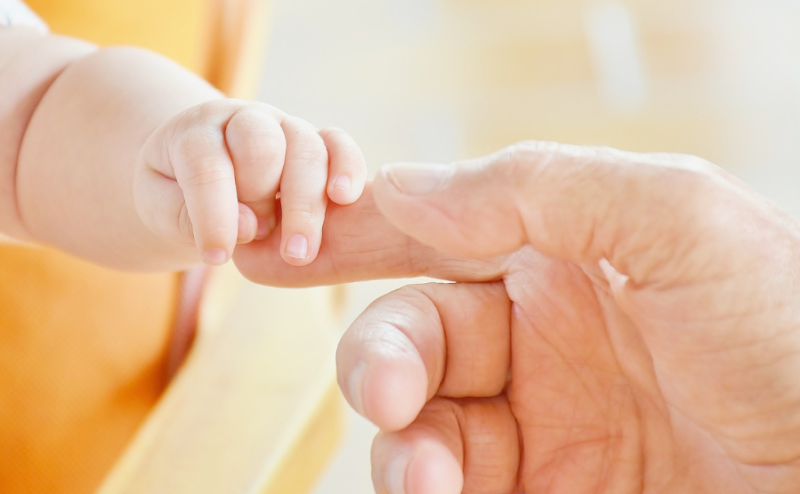 Gambar tangan bayi dan orang tua yang saling memegang.