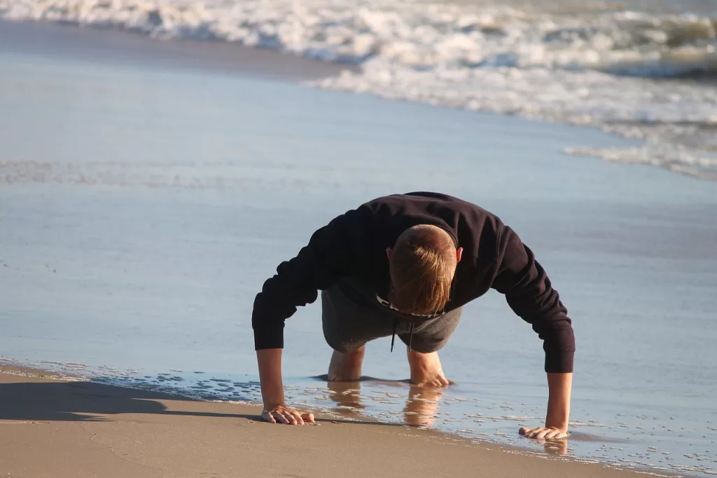 Gambar seorang pria sedang melakukan gerakan push up di bibir pantai, ilustrasi kalimat motivasi diet agar berhasil.