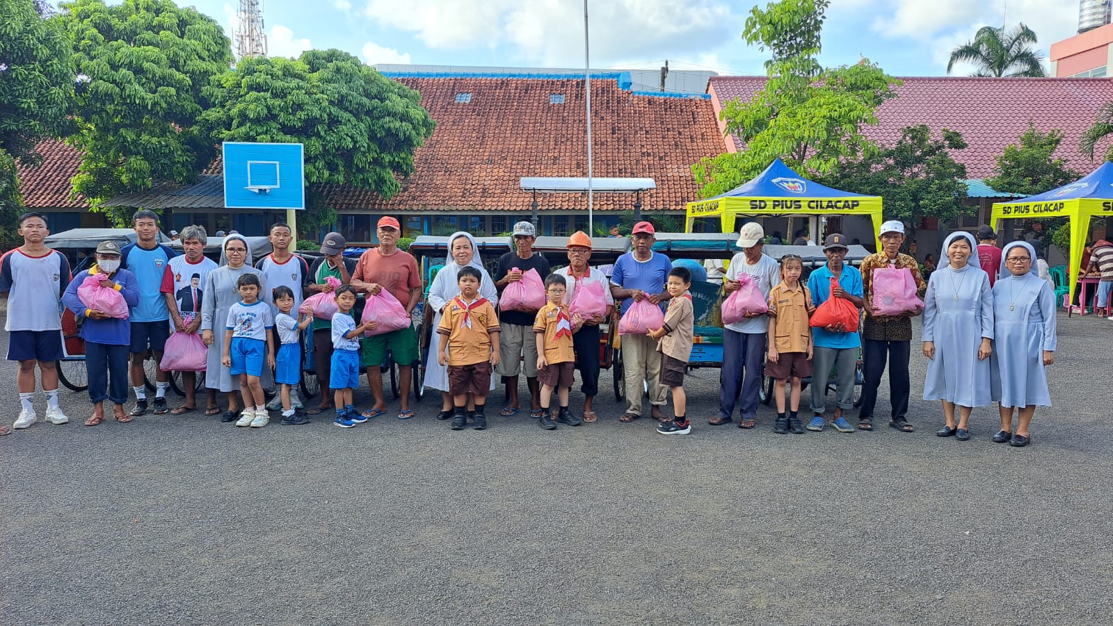 Siswa dan guru Perguruan Pius Cilacap membagikan paket sembako kepada warga kurang mampu. (Ulul Azmi)